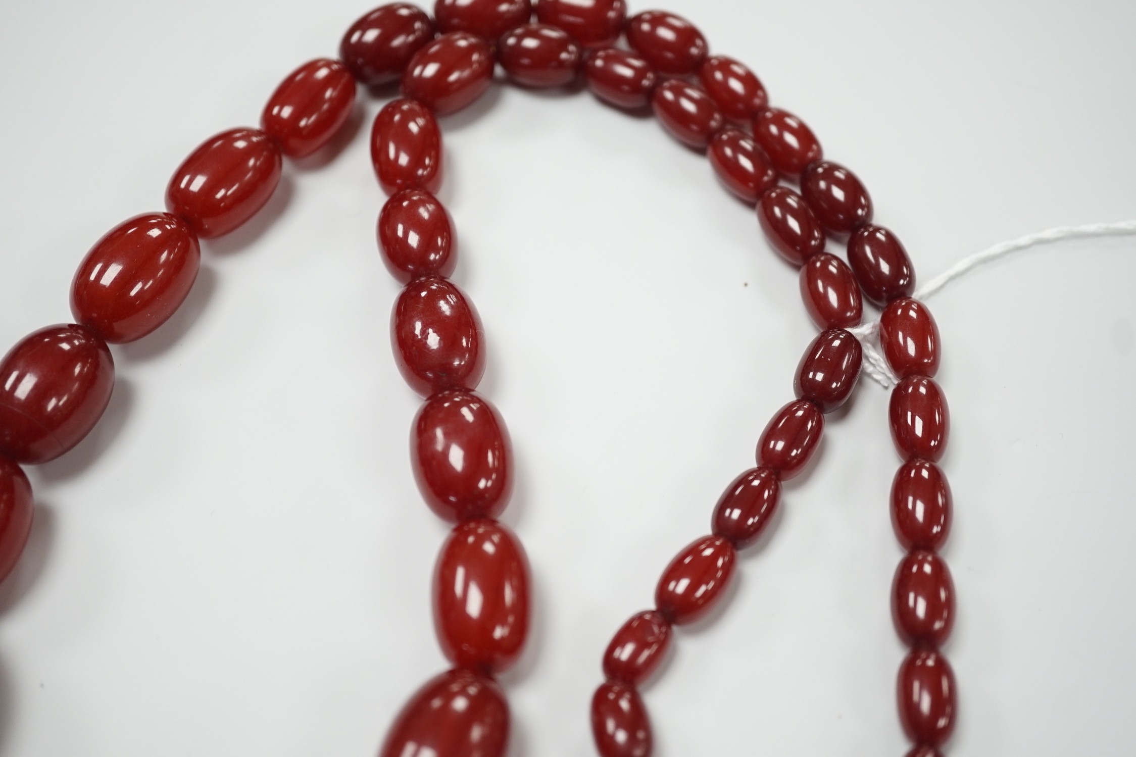 A single strand graduated simulated oval cherry amber necklace, 82cm, gross weight 113 grams.